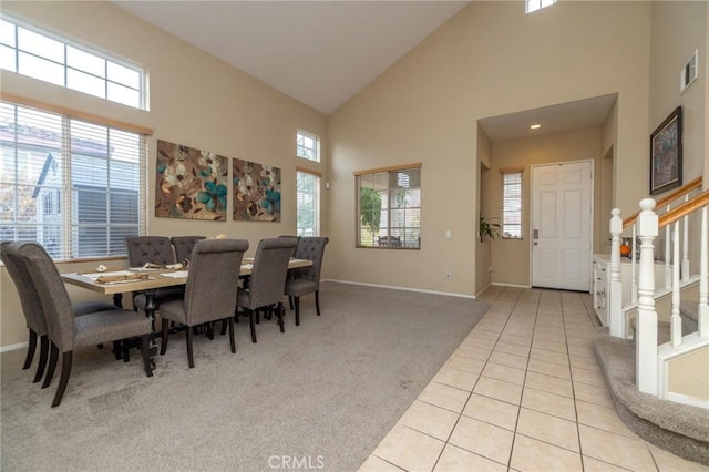 dining space with high vaulted ceiling and light tile patterned flooring