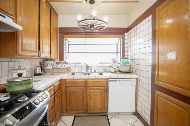 kitchen with white appliances, sink, light tile patterned floors, tile countertops, and a chandelier