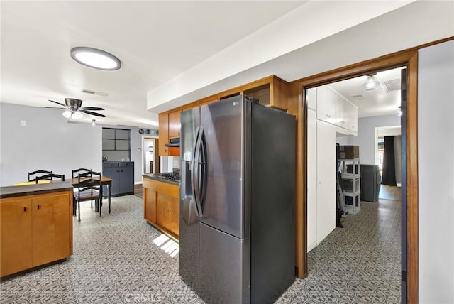 1938 Colusa, Corning, CA 96021 - kitchen with stainless steel fridge, dark countertops, light floors, ceiling fan, and brown cabinetry