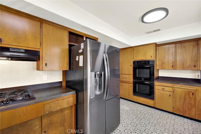 kitchen featuring double oven, stainless steel fridge, exhaust hood, and gas cooktop