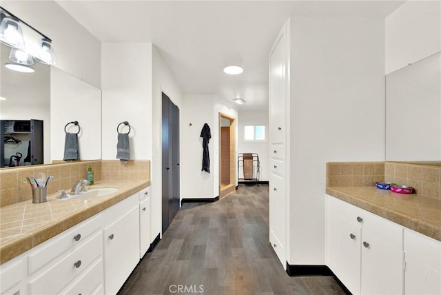 bathroom with vanity, hardwood / wood-style flooring, and tasteful backsplash