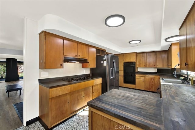 1938 Colusa, Corning, CA 96021 - kitchen featuring under cabinet range hood, black appliances, dark countertops, and brown cabinetry