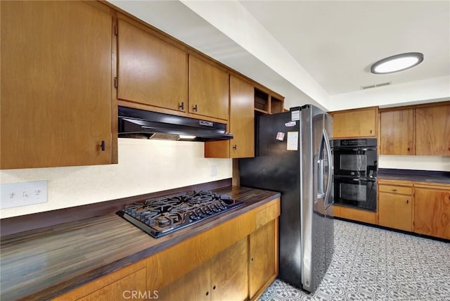 1938 Colusa, Corning, CA 96021 - kitchen featuring under cabinet range hood, black appliances, dark countertops, and brown cabinetry