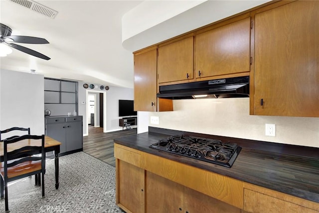 1938 Colusa, Corning, CA 96021 - kitchen with black gas stovetop, under cabinet range hood, ceiling fan, dark countertops, and brown cabinetry