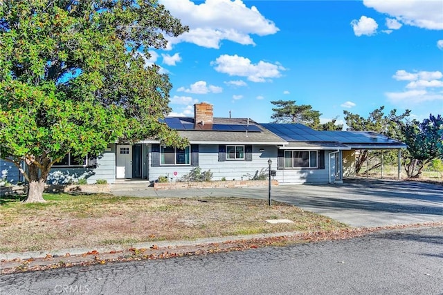 1938 Colusa, Corning, CA 96021 - ranch-style home with a carport, driveway, roof mounted solar panels, a chimney, and a front lawn