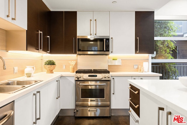 kitchen featuring appliances with stainless steel finishes, dark brown cabinetry, sink, white cabinets, and dark hardwood / wood-style floors