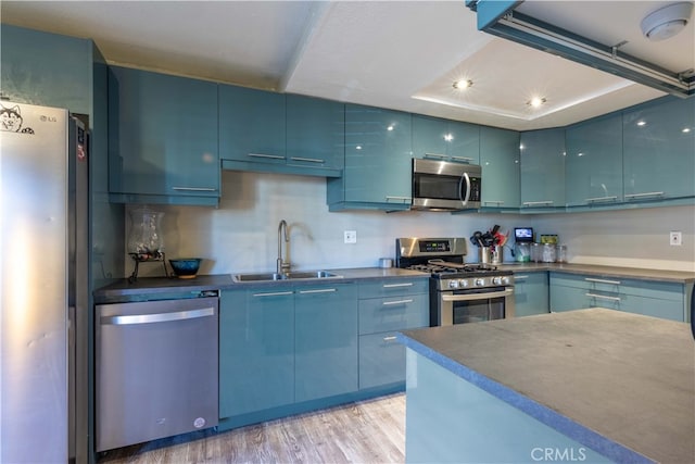 kitchen featuring light hardwood / wood-style floors, sink, stainless steel appliances, and blue cabinets