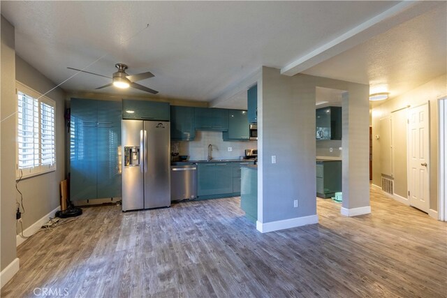 kitchen featuring ceiling fan, hardwood / wood-style floors, appliances with stainless steel finishes, and tasteful backsplash