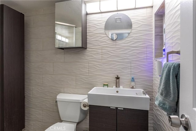 bathroom featuring tile walls, toilet, and vanity