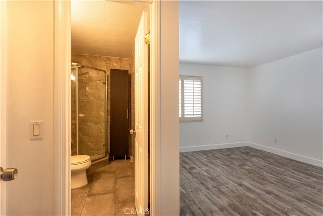 bathroom featuring a shower with shower door and toilet