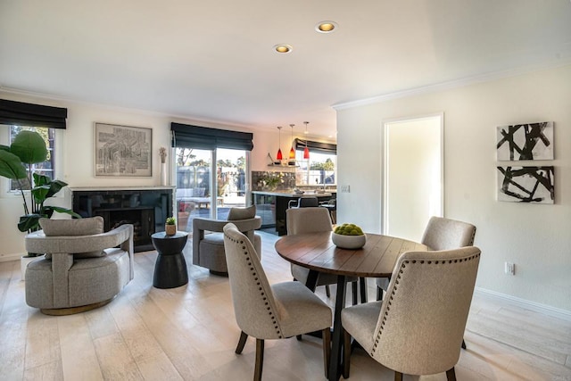 dining space featuring light wood-type flooring and crown molding