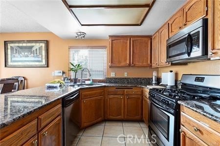 kitchen featuring light tile patterned floors, stainless steel appliances, dark stone countertops, and sink