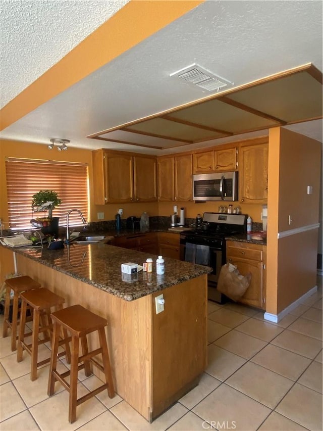 kitchen with black range, light tile patterned floors, and kitchen peninsula