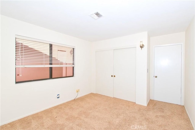 unfurnished bedroom featuring light carpet and a closet