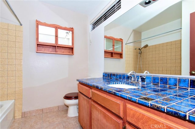 full bathroom featuring tile patterned floors, tiled shower / bath, vanity, and toilet