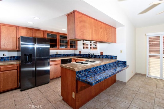 kitchen with refrigerator with ice dispenser, lofted ceiling, kitchen peninsula, and light tile patterned floors