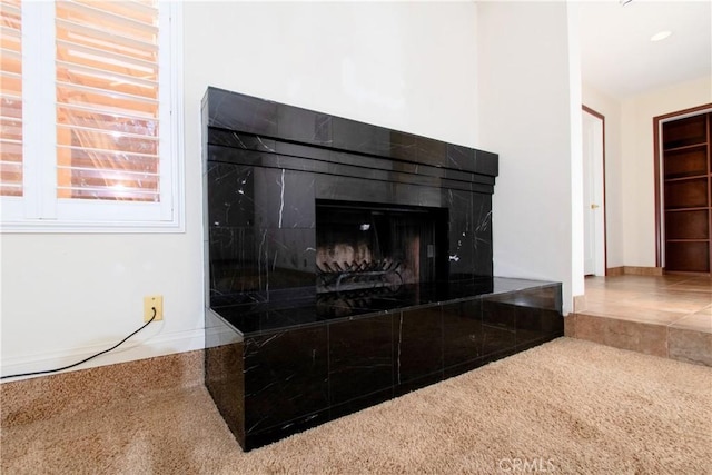 interior details with a tile fireplace and carpet flooring