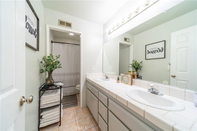 bathroom with toilet, vanity, and tile patterned flooring