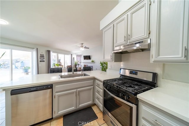 kitchen featuring appliances with stainless steel finishes, lofted ceiling, kitchen peninsula, light tile patterned flooring, and ceiling fan