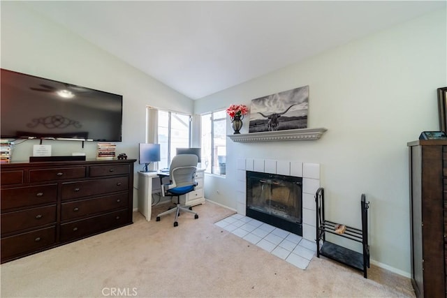 office space featuring lofted ceiling, light colored carpet, and a tiled fireplace