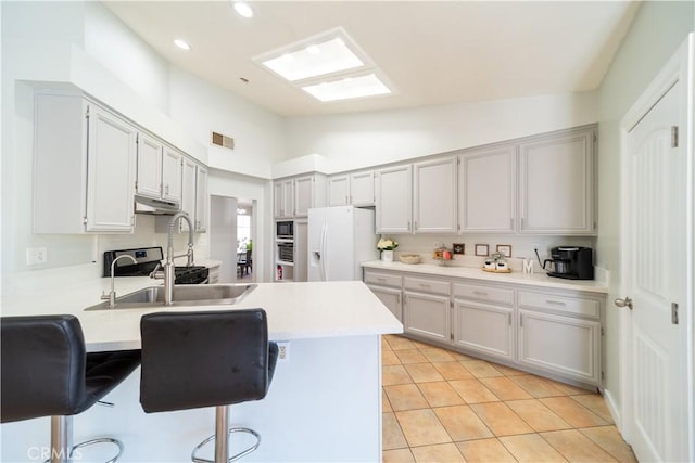 kitchen with a breakfast bar, white fridge with ice dispenser, kitchen peninsula, and light tile patterned flooring