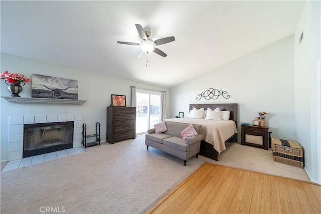 bedroom featuring ceiling fan, a fireplace, wood-type flooring, and vaulted ceiling