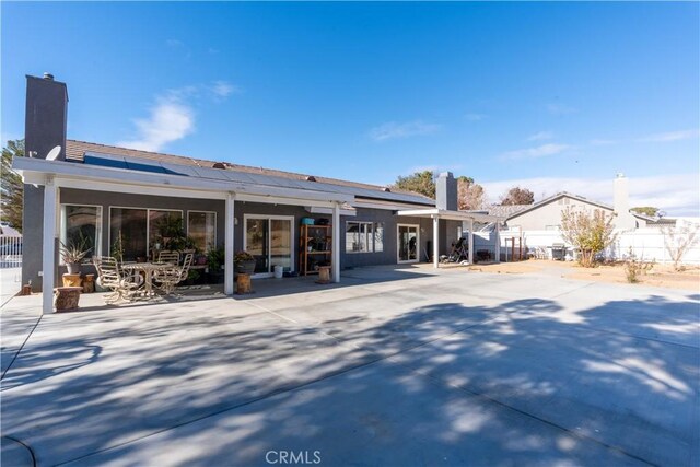 rear view of property featuring a pergola, solar panels, and a patio