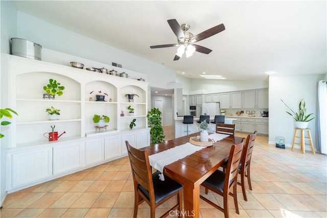 tiled dining area featuring ceiling fan, built in shelves, and lofted ceiling