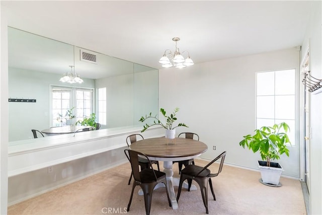 dining space with light colored carpet and a notable chandelier