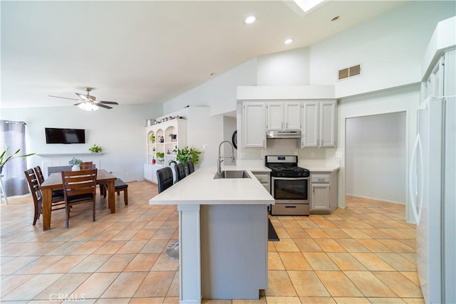 kitchen featuring white fridge, sink, vaulted ceiling, ceiling fan, and stainless steel range with gas cooktop