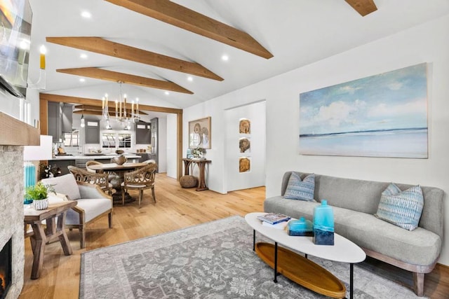 living room with light wood-type flooring, a chandelier, a fireplace, and lofted ceiling with beams