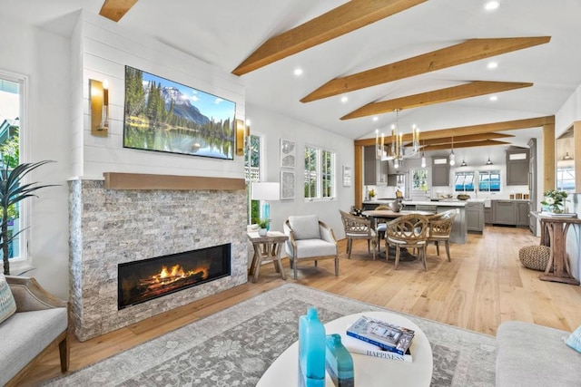 living room featuring lofted ceiling with beams, a stone fireplace, and wood-type flooring