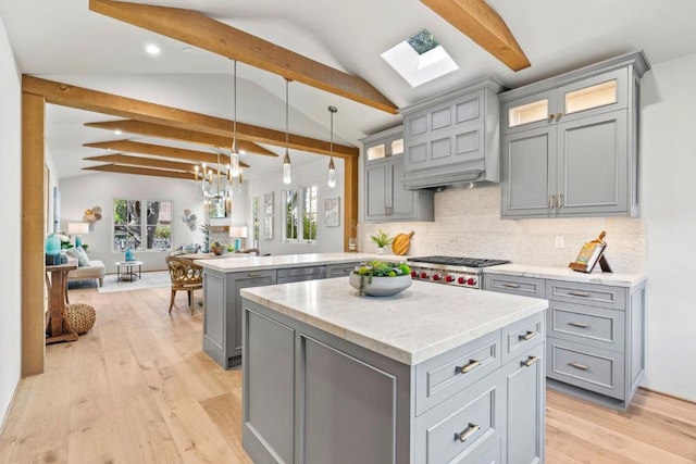 kitchen featuring kitchen peninsula, gray cabinetry, decorative backsplash, hanging light fixtures, and a center island