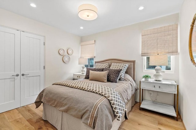 bedroom with a closet, multiple windows, and light hardwood / wood-style flooring