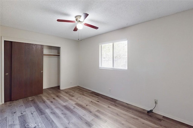 unfurnished bedroom with a textured ceiling, a closet, light hardwood / wood-style floors, and ceiling fan