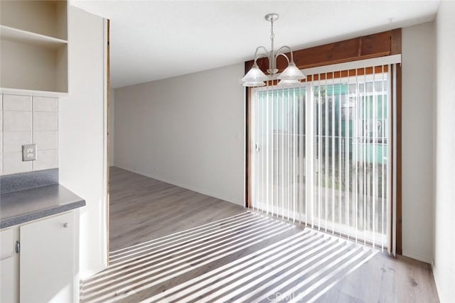 unfurnished dining area featuring light hardwood / wood-style floors and a notable chandelier