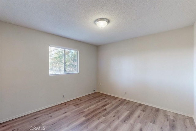 empty room with light hardwood / wood-style floors and a textured ceiling