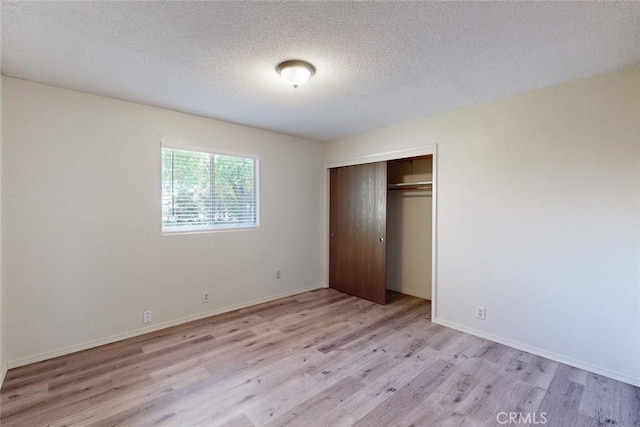 unfurnished bedroom featuring light hardwood / wood-style floors, a textured ceiling, and a closet