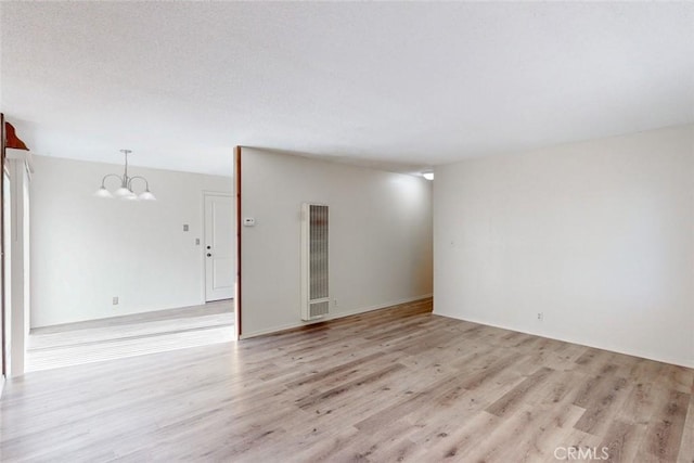 unfurnished room featuring light wood-type flooring and a notable chandelier