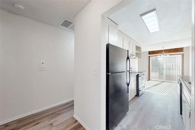 kitchen featuring black refrigerator, white electric range oven, light hardwood / wood-style floors, white cabinetry, and hanging light fixtures