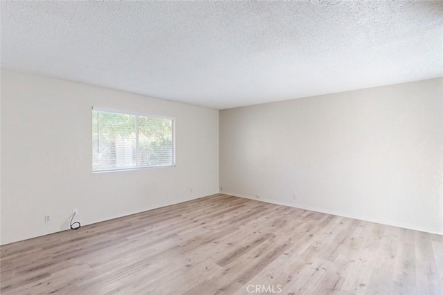 spare room with a textured ceiling and light hardwood / wood-style flooring