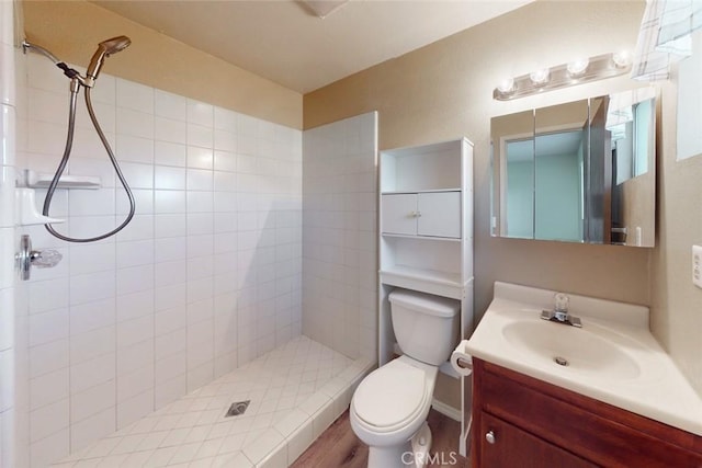 bathroom with toilet, hardwood / wood-style floors, vanity, and a tile shower