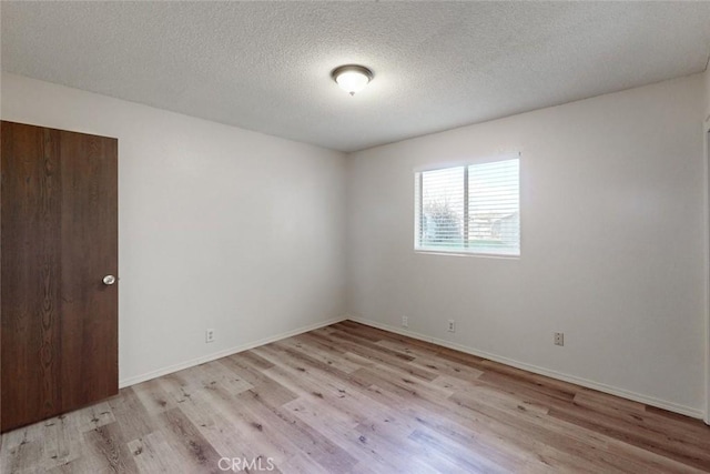 unfurnished room with a textured ceiling and light hardwood / wood-style flooring