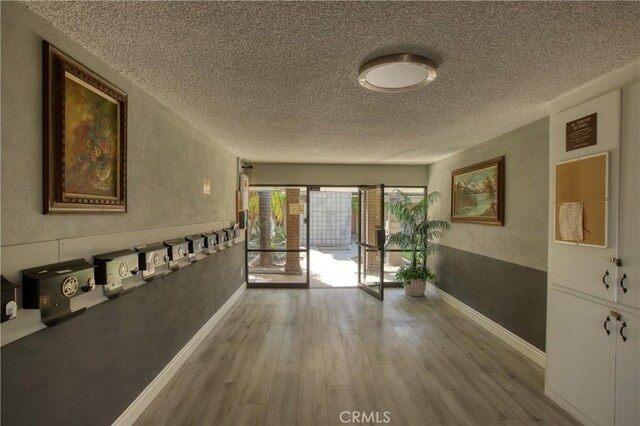 hallway with a textured ceiling and hardwood / wood-style flooring