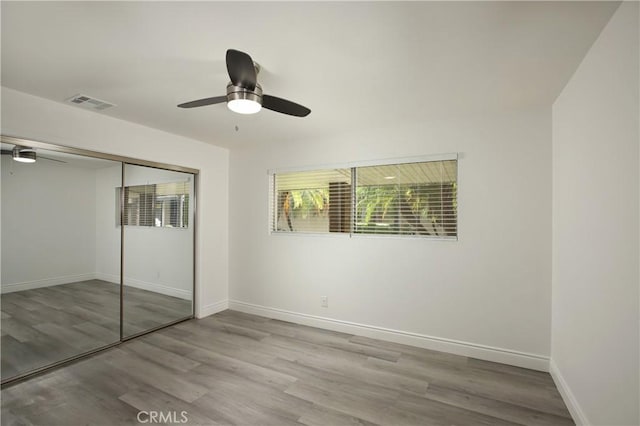 unfurnished bedroom featuring light hardwood / wood-style flooring, a closet, and ceiling fan