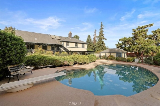 view of pool with a patio area and a diving board