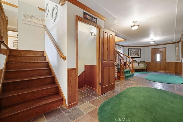 stairway with ornamental molding and wooden walls