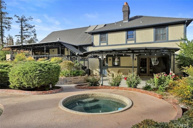 back of house featuring an in ground hot tub and a patio