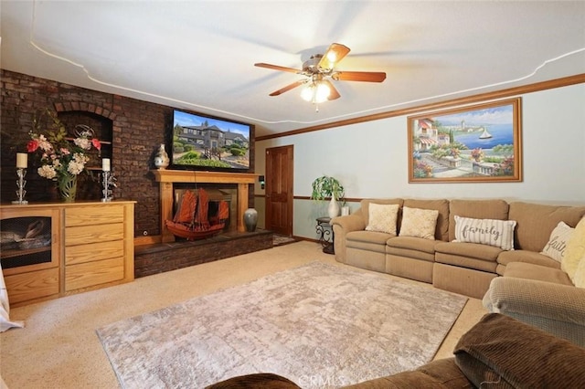 living room featuring ceiling fan, a large fireplace, light colored carpet, and crown molding