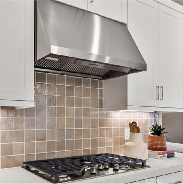 kitchen featuring tasteful backsplash, white cabinetry, and ventilation hood